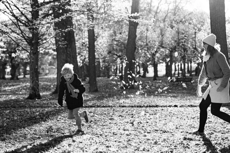 photographe famille faisant une bataille de feuilles mortes