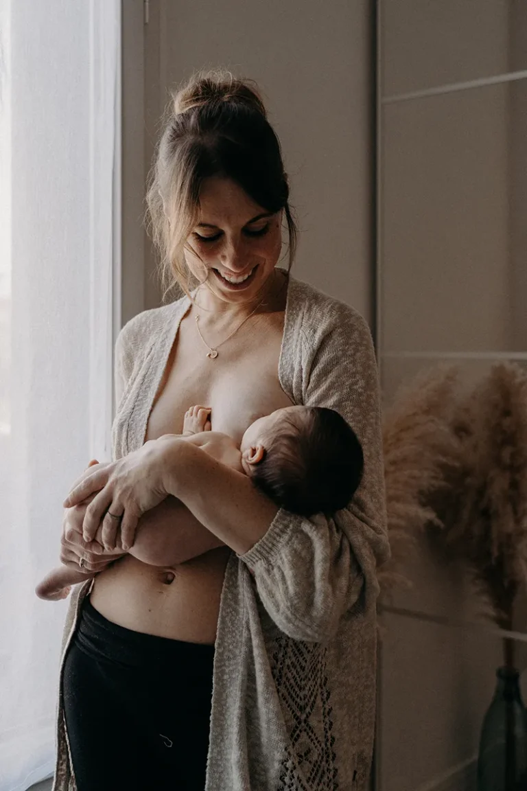 photographe bébé d'une mère dans sa chambre qui allaite son bébé en peau à peau