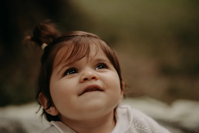 photographe bébé du visage d'une petite fille qui regarde le ciel en forêt