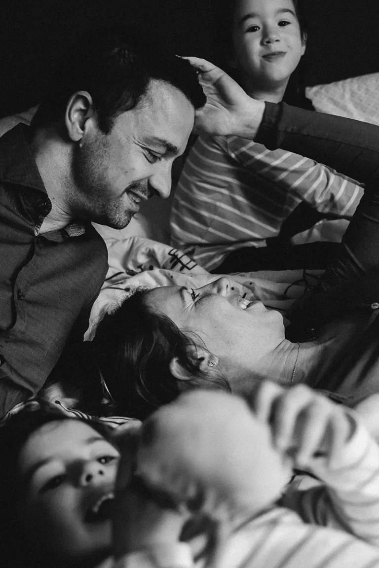 photographe famille de parents et enfants qui jouent sur le lit chez eux à Paris
