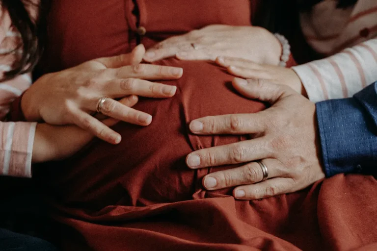 photographe grossesse du ventre de femme enceinte avec les mains de son amoureux et de ses filles posées dessus