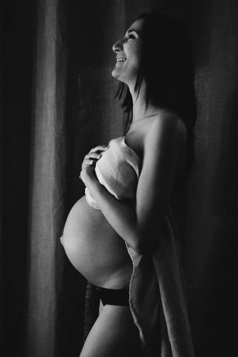photographe grossesse d'une femme enceinte à son domicile avec le ventre dénudé