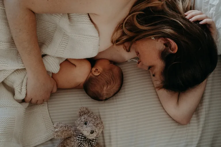 photographe bébé Paris d'une mère dans son lit qui allaite son nouveau né