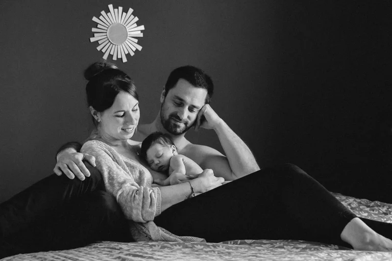 photographe bébé de parents faisant un câlin à leur bébé sur leur lit à paris