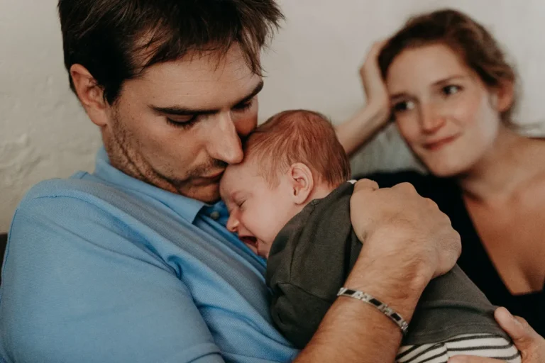 photographe bébé paris d'un papa qui tient son bébé et la maman qui les regarde avec tendresse