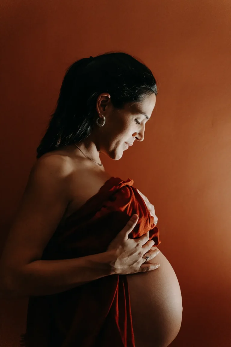 femme enceinte dans sa chambre qui regarde son ventre nu avec tendresse photographiée par une photographe grossesse à paris