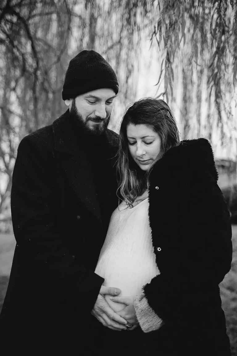 couple dans la nature hivernale qui regarde le ventre de la femme enceinte photographié par une photographe grossesse à paris