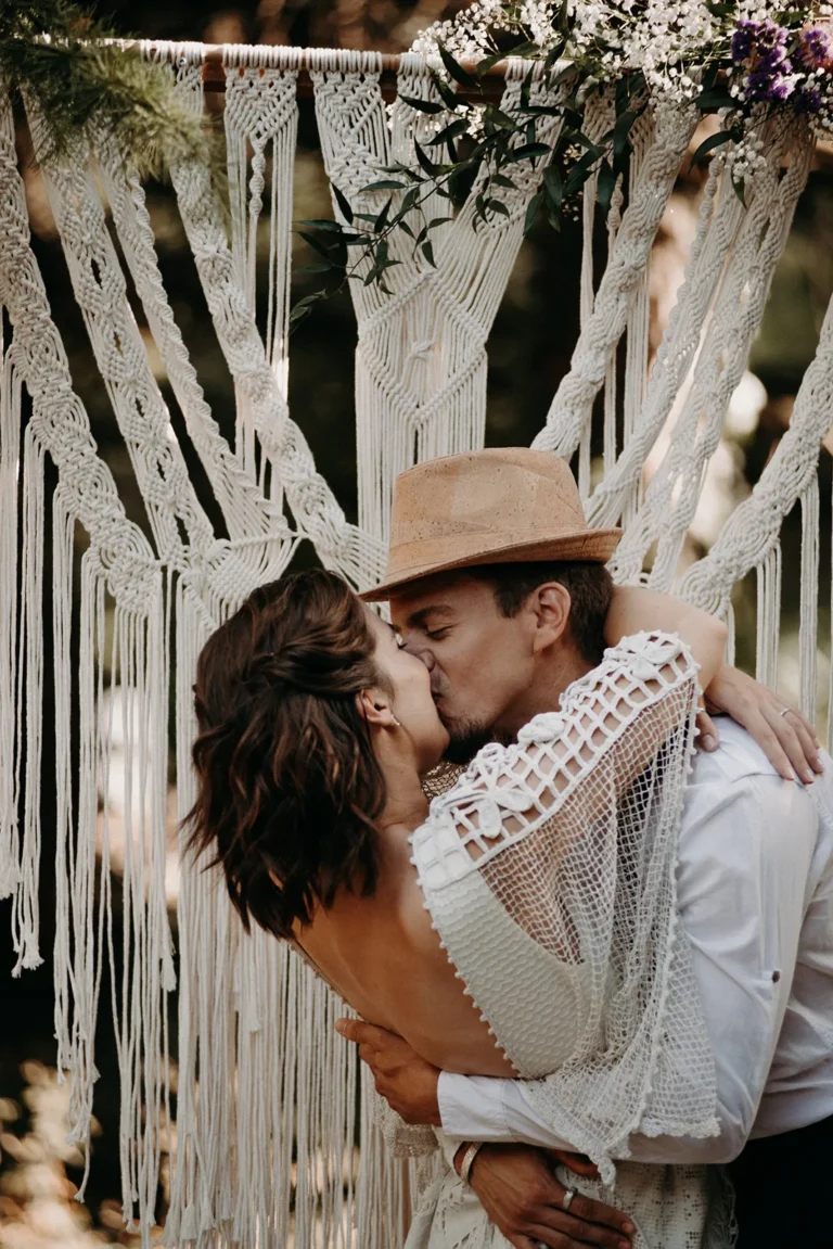 mariés s'embrassant devant une arche de cérémonie laïque à leur mariage à Paris immortalisés par une photographe